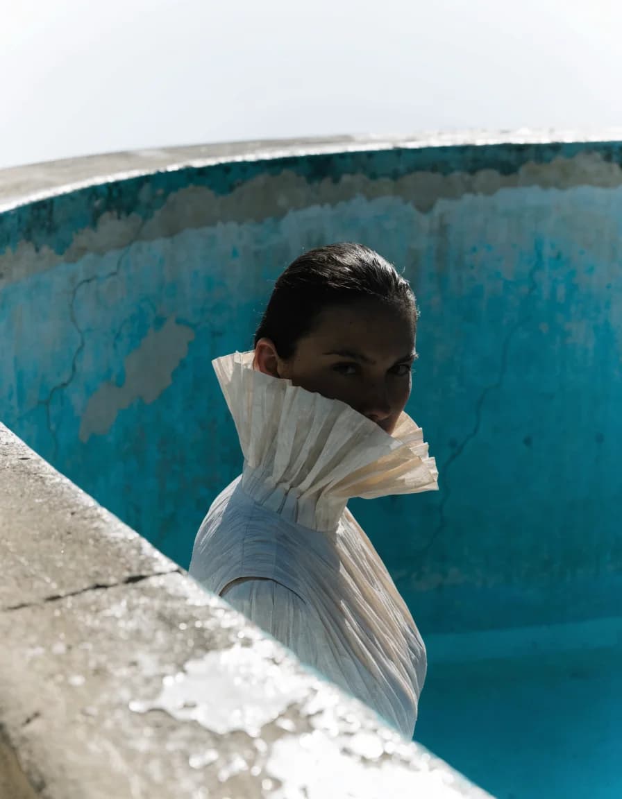 Woman in a pleated collar standing in an empty blue pool